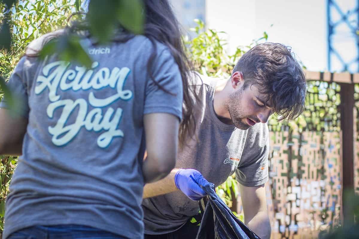 Two Aldrich employees, one man picking up trash and one women with her back facing the camera, during Aldrich's Action Day of community service.