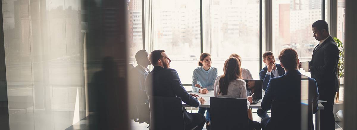 A group of colleagues in a meeting room looking at their presenter.