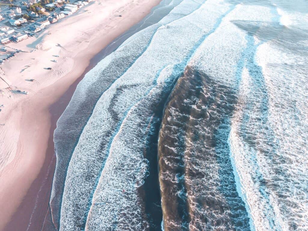 Aerial view of the ocean waves, sand, and houses