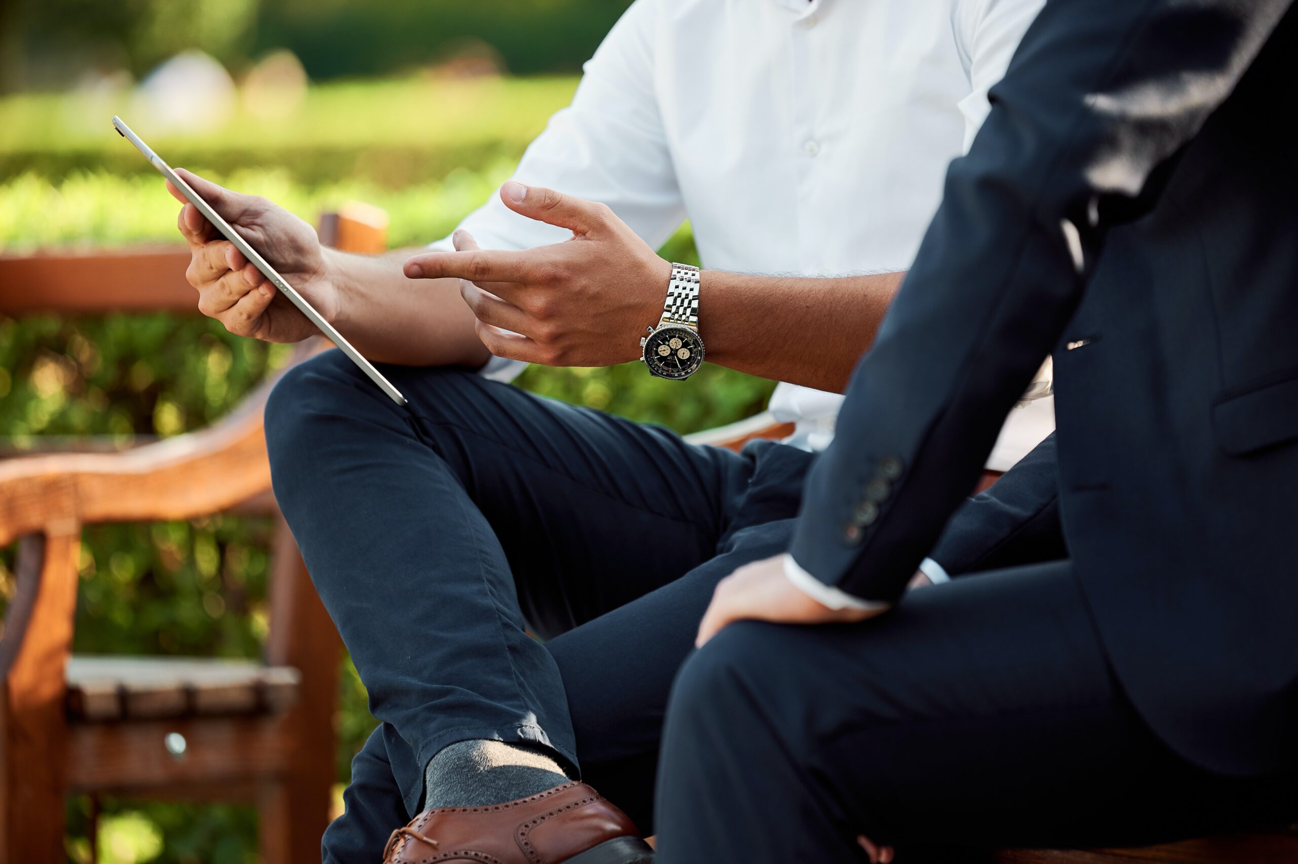 two businessmen discuss quality of earnings reports in a park