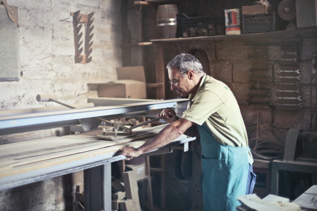 Manufacturing worker saws through a piece of lumber