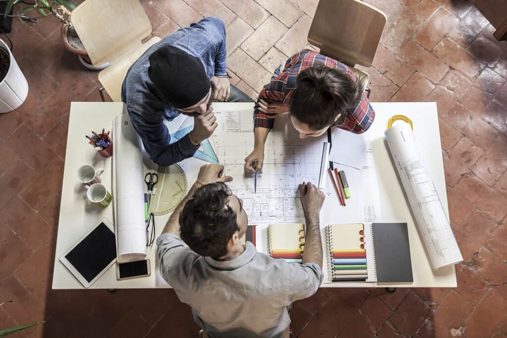 team of architects and engineers look at blueprints on a wooden table