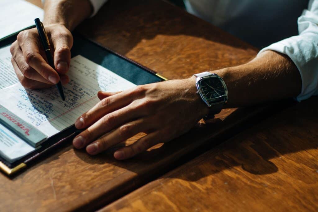 Business owner writes on notepad on wooden table