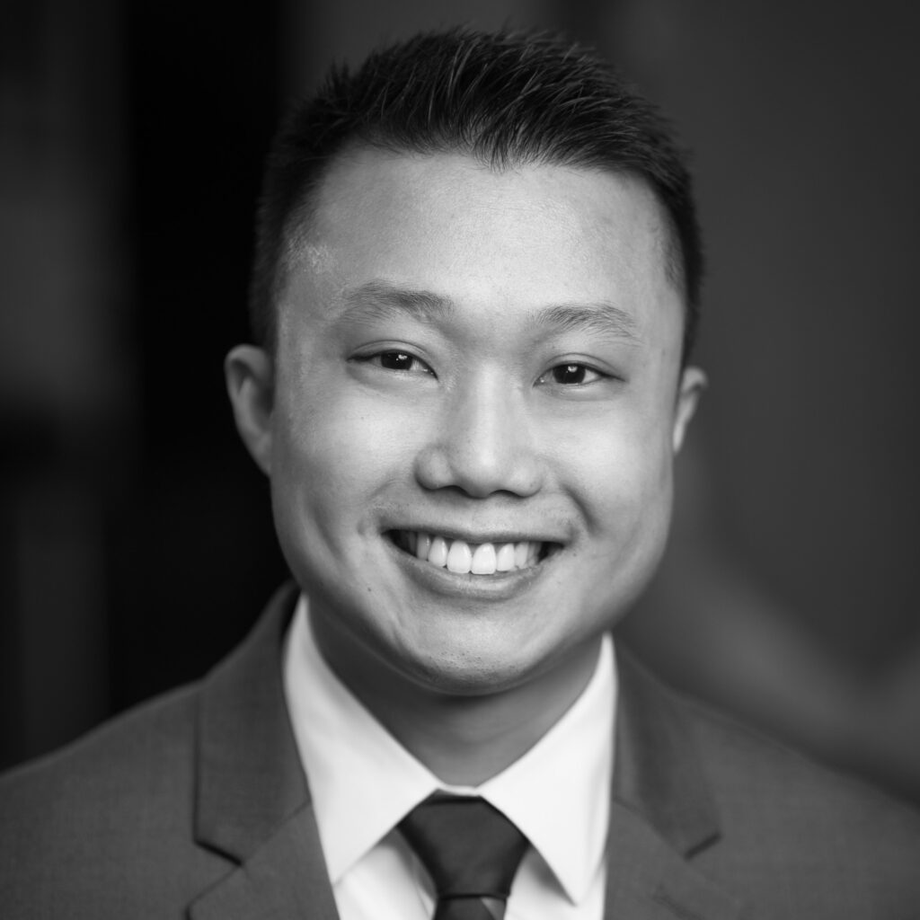 Justin Tat's headshot in black and white in indoor office space