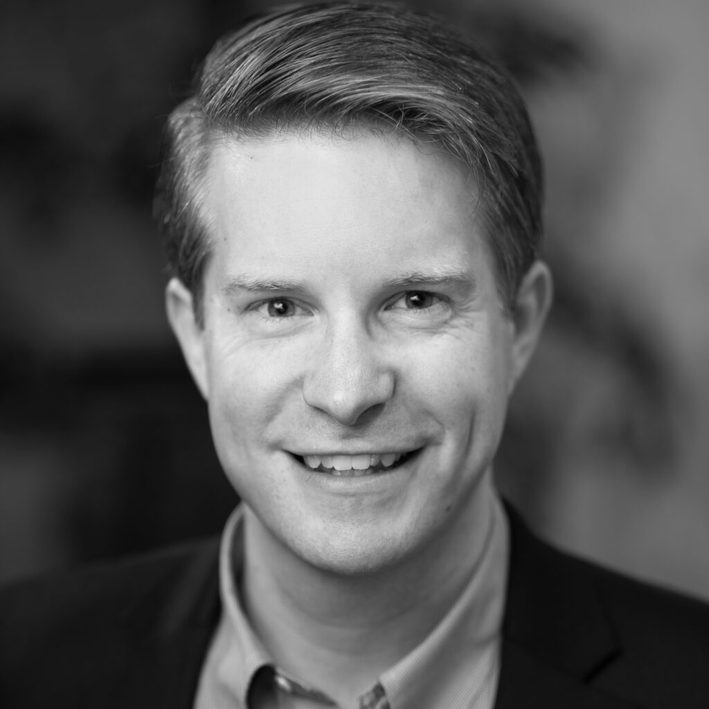 Tom Gilbers' headshot in black and white in office setting.